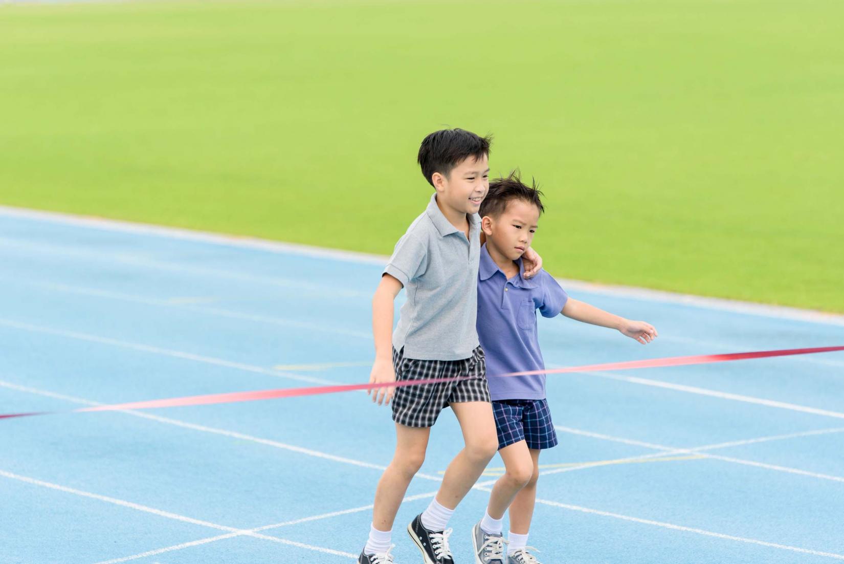 Young boy carries friend to finish line